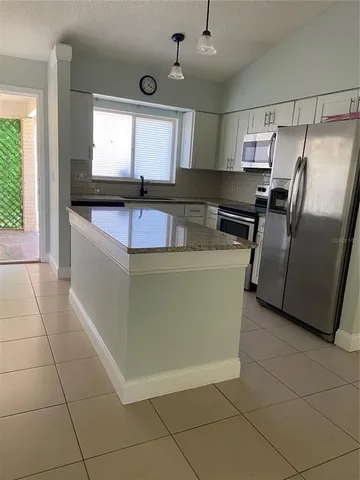 a kitchen with stainless steel appliances granite countertop a sink a microwave a refrigerator and a granite counter tops