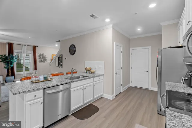 a kitchen with a sink dishwasher refrigerator and wooden floor