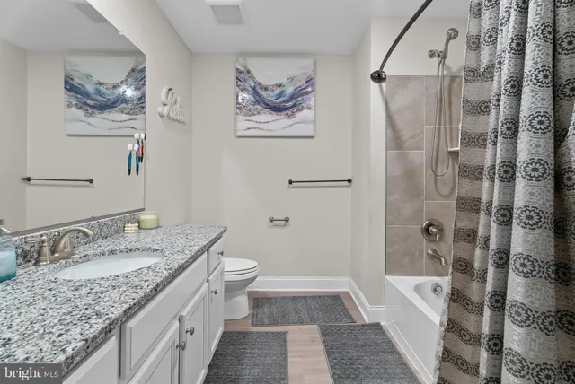 a bathroom with a granite countertop sink a toilet and shower