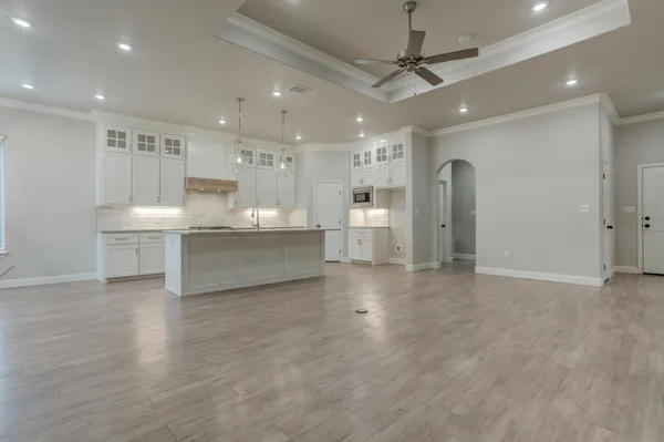 a large kitchen with kitchen island a stove a sink dishwasher a refrigerator and white cabinets with wooden floor
