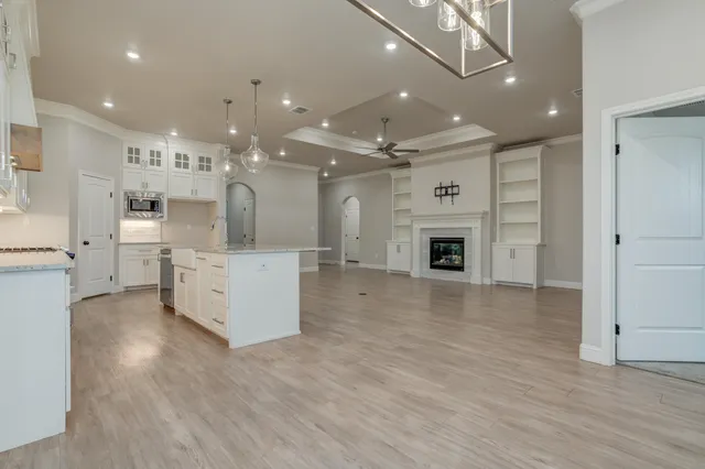 a large kitchen with granite countertop a large counter top appliances and cabinets