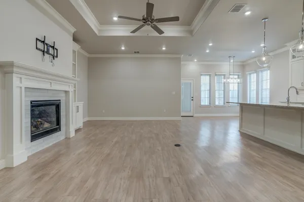 a view of an empty room with wooden floor and a fireplace