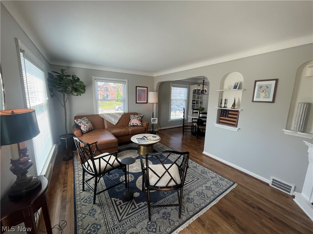 3471 Warren Road Cleveland, OH 44111 - Photo 5 of 17 Living room featuring arched walkways, dark wood-style floors, and a chandelier