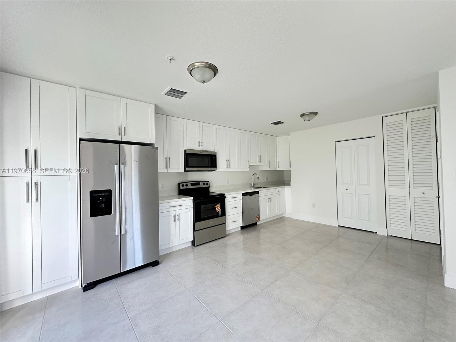 11278 Southwest 187th Street, Unit 11278 Miami, FL 33157 - Photo 4 of 16 a large white kitchen with refrigerator a stove a sink and white cabinets