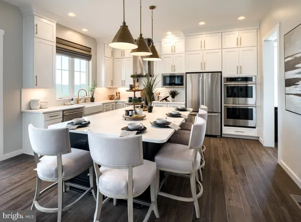 a dining room with stainless steel appliances kitchen island granite countertop a table chairs and a refrigerator