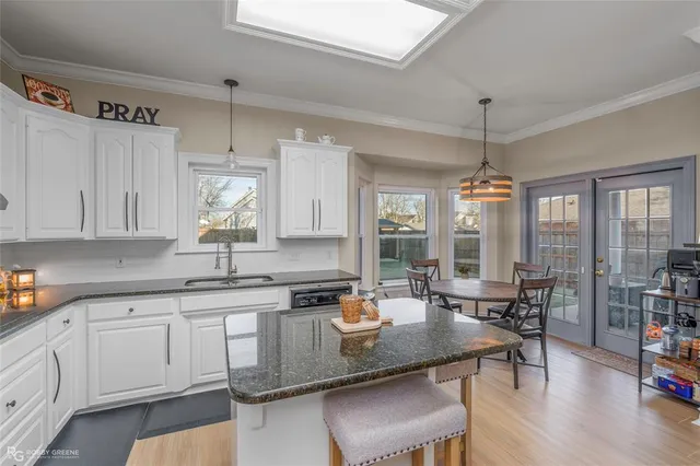 a kitchen with a dining table chairs cabinets wooden floor and appliances