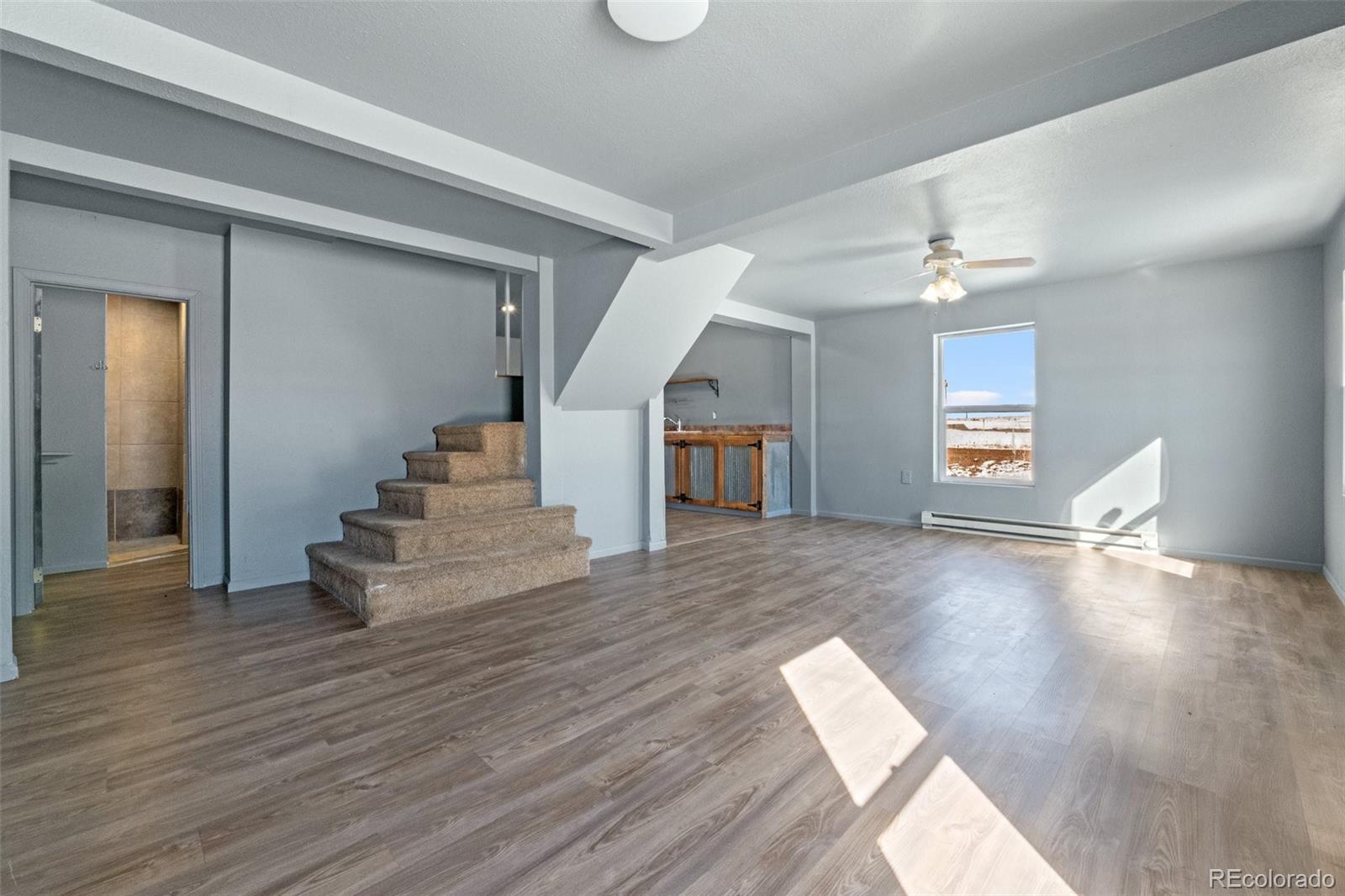 620 Hospital Road Brush, CO 80723 - Photo 6 of 24 a view of an empty room and kitchen with wooden floor