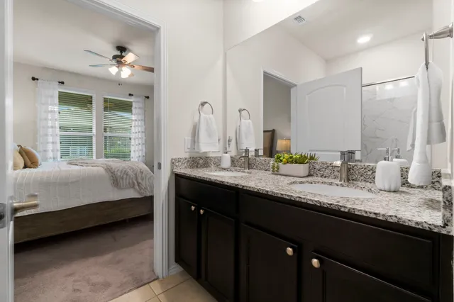 a en suite bathroom with a granite countertop sink and a large mirror