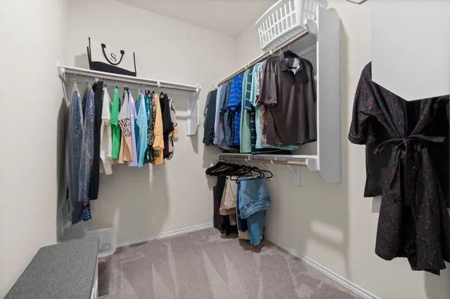 a view of walk in closet with clothes and shoes