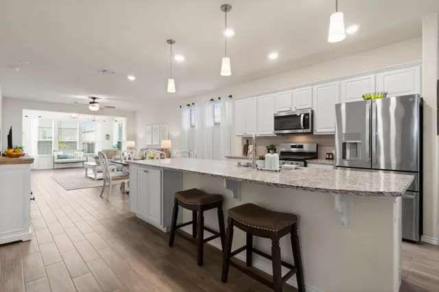 a kitchen with stainless steel appliances a microwave a stove a sink a center island and furniture