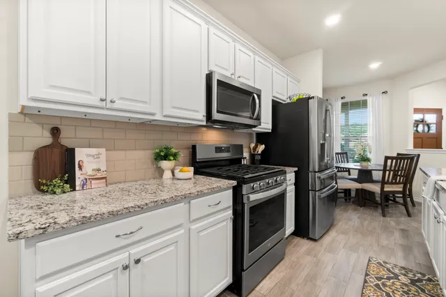 a kitchen with stainless steel appliances granite countertop a stove refrigerator sink and cabinets