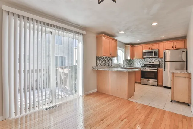 a kitchen with stainless steel appliances granite countertop a refrigerator a sink dishwasher a stove and white countertops with wooden floor