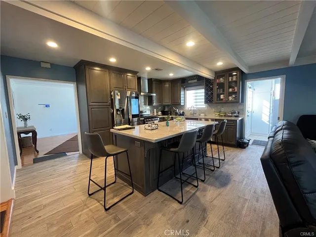 a kitchen with stainless steel appliances kitchen island granite countertop a table chairs sink and wooden floor