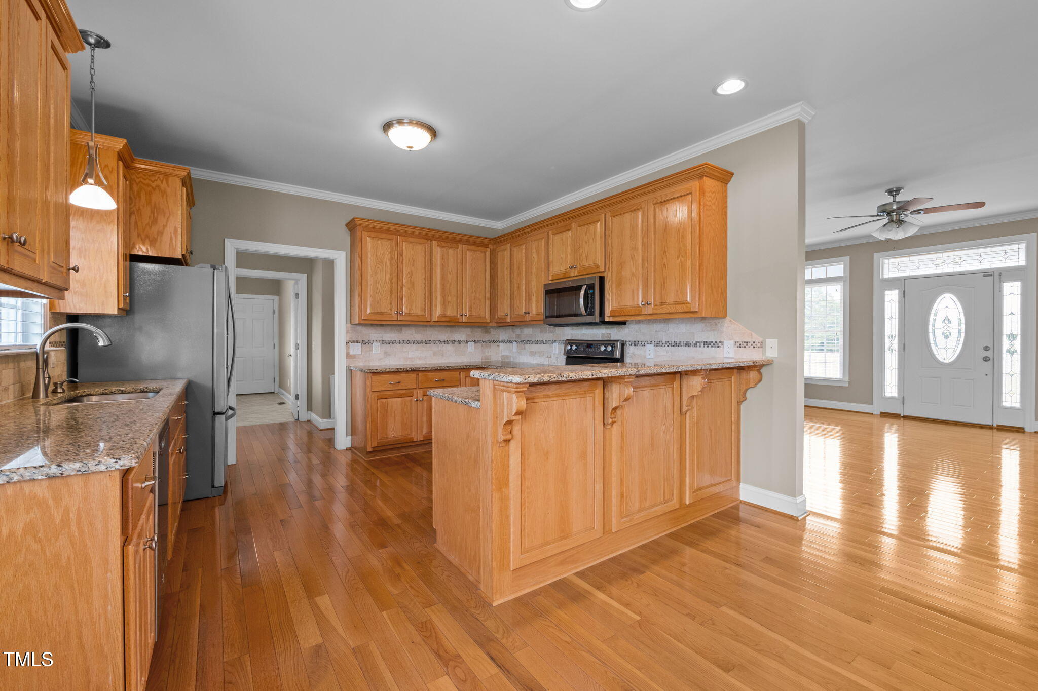 5556 Hurdle Mills Road Roxboro, NC 27574 - Photo 19 of 53 a kitchen with stainless steel appliances granite countertop a stove a sink a refrigerator white cabinets and wooden floor next to a window