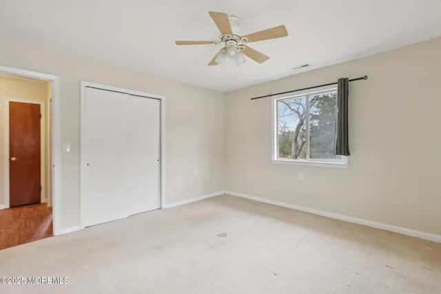 an empty room with windows and fan