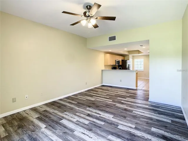 a view of empty room with wooden floor and ceiling fan