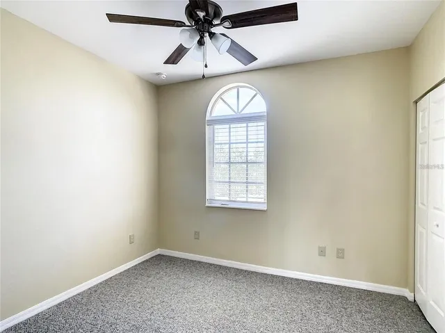 an empty room with ceiling fan and window