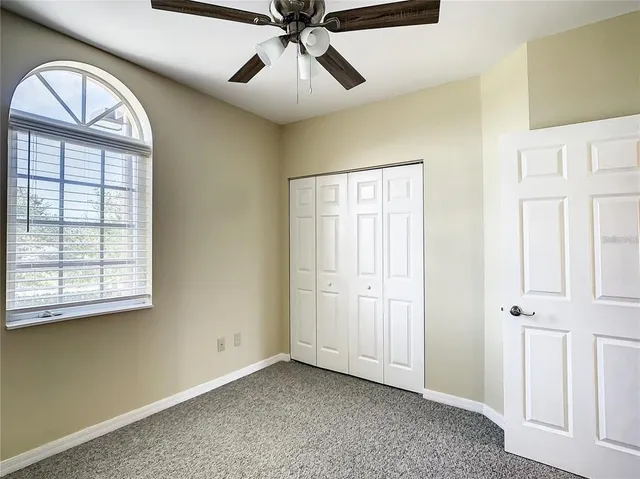 an empty room with windows and fan