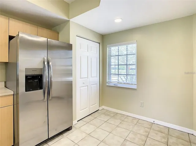 a view of a refrigerator in kitchen and wooden cabinets