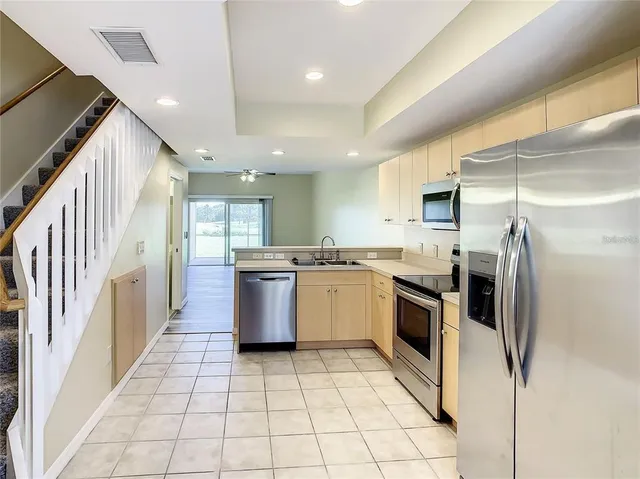 a large kitchen with a large counter top a stove a sink dishwasher a refrigerator and cabinets