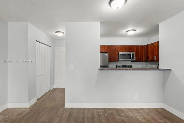 a view of a kitchen with stainless steel appliances wooden floor and a window