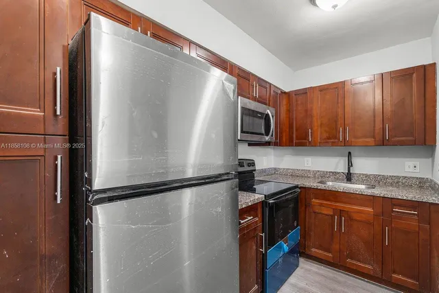 a kitchen with a sink a refrigerator a microwave and cabinets