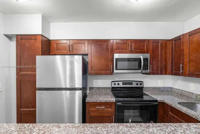 a kitchen with stainless steel appliances granite countertop a refrigerator a stove and a sink