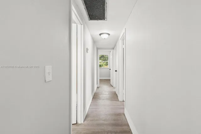 a view of a hallway with wooden floor and a bathroom