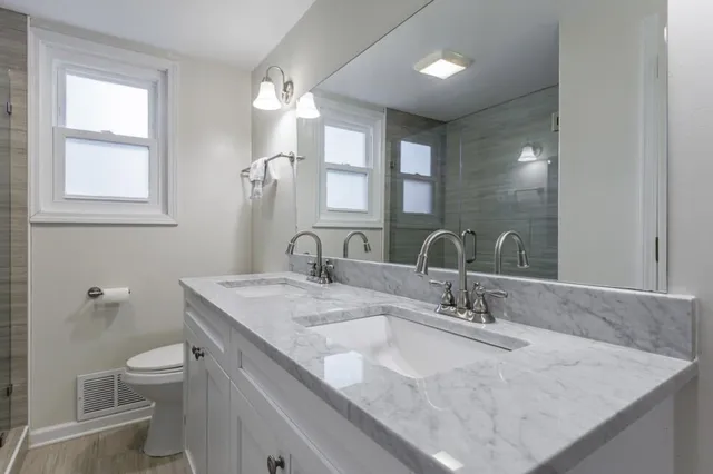 a bathroom with a granite countertop sink a toilet and a mirror