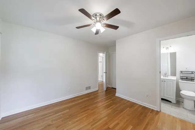 an empty room with wooden floor and a ceiling fan