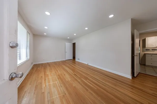 a view of empty room with wooden floor and window