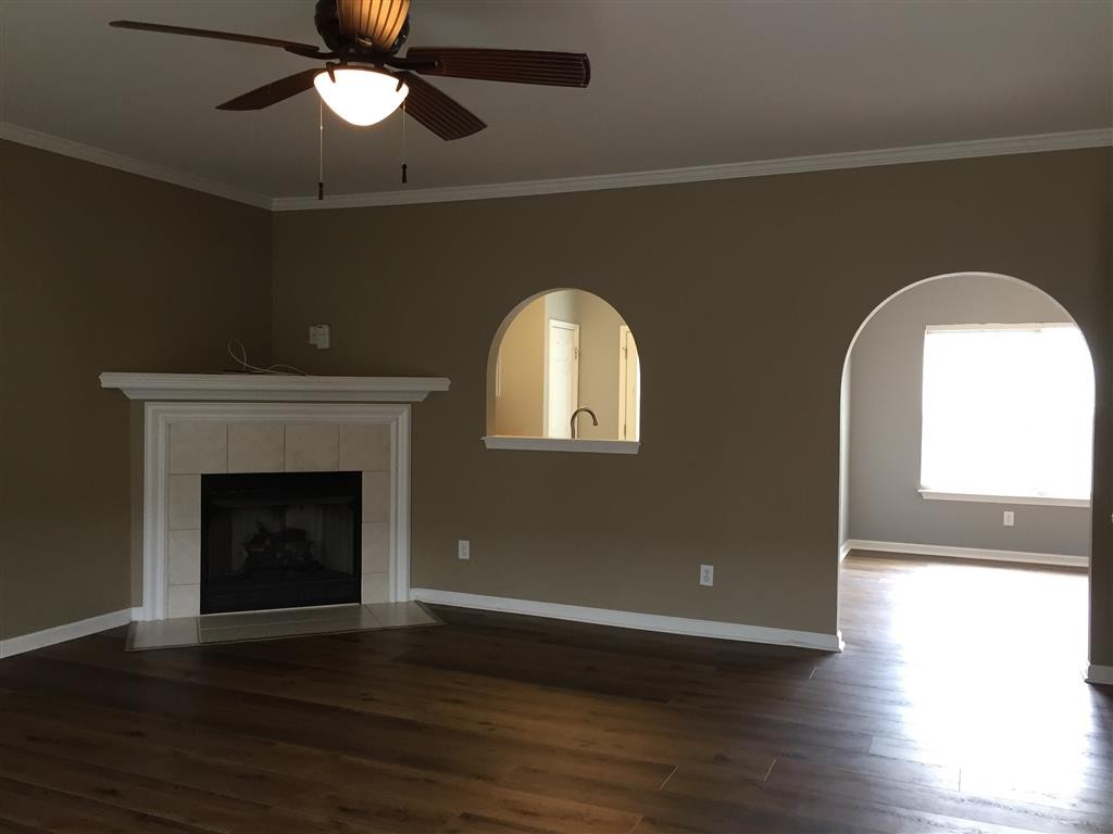 1101 Downs Boulevard, Unit 125 Franklin, TN 37064 - Photo 4 of 8 a view of a livingroom with wooden floor a ceiling fan and a fireplace