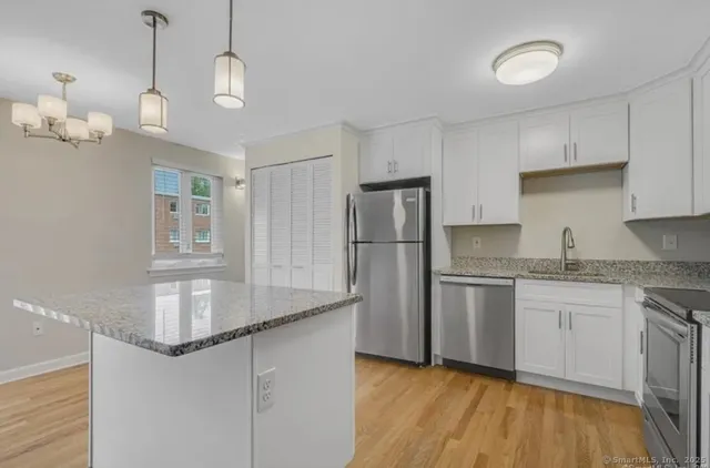 a kitchen with stainless steel appliances granite countertop a sink a refrigerator and a stove