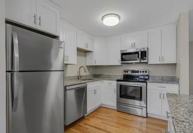 a kitchen with stainless steel appliances granite countertop a refrigerator stove a sink and a microwave