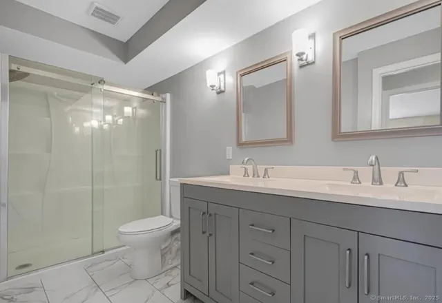a bathroom with a double vanity sink toilet and shower