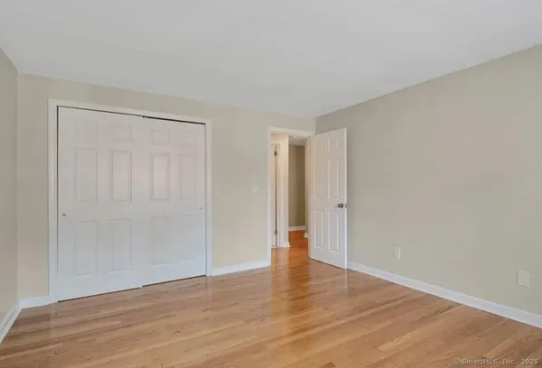 a view of an empty room with wooden floor and closet