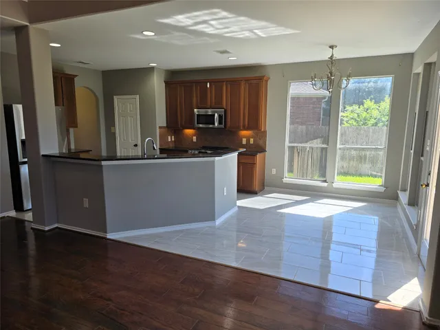 a kitchen with stainless steel appliances granite countertop a refrigerator a stove and a wooden floors