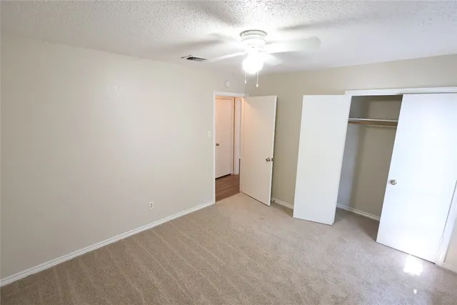 an empty room with closet and a ceiling fan