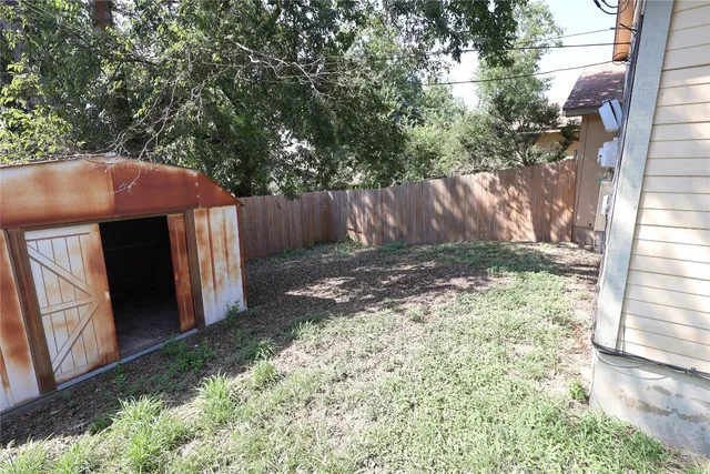 a view of a backyard with a tree and wooden fence