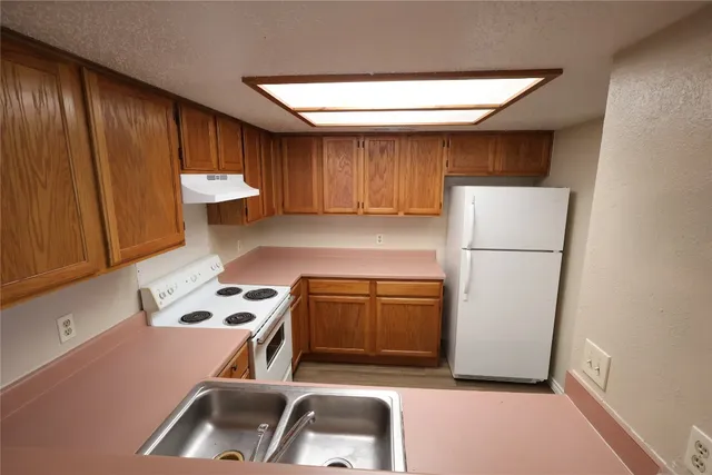 a kitchen with a refrigerator sink and cabinets