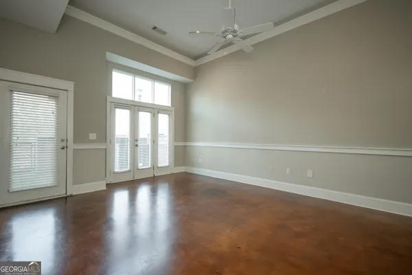 an empty room with wooden floor and windows with curtains