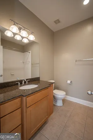 a bathroom with a granite countertop sink a toilet and a mirror