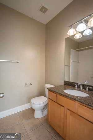 a bathroom with a granite countertop sink a toilet and a mirror