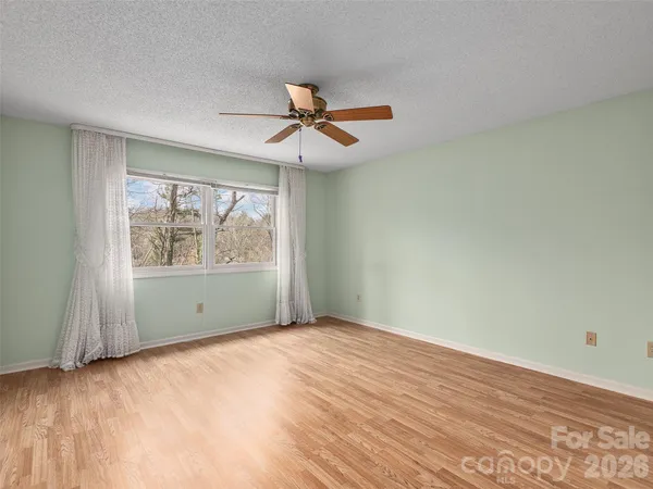 an empty room with wooden floor fan and windows