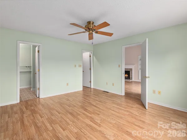a view of empty room with wooden floor and ceiling fan