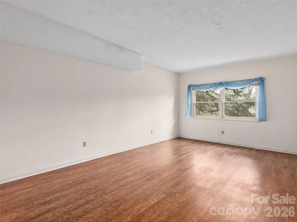 an empty room with wooden floor and window