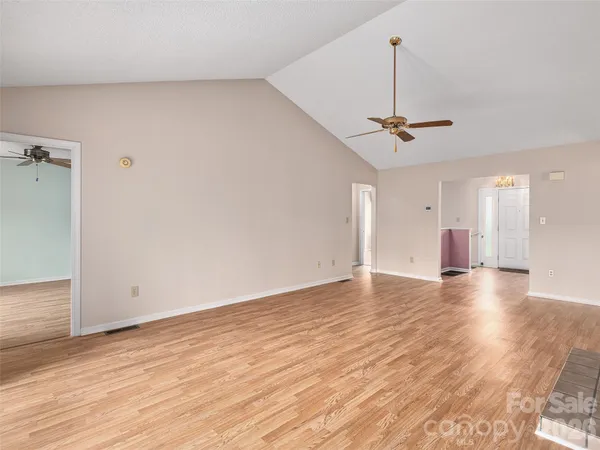 a view of empty room with wooden floor and ceiling fan