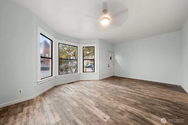 a view of an empty room with a window and wooden floor