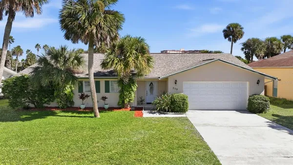 a front view of a house with a garden and palm trees