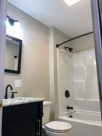 a bathroom with a sink toilet a mirror a vanity and shower